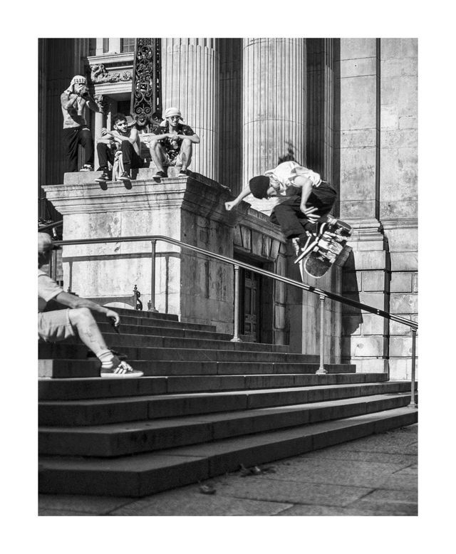 A skateboarder beside stone columns